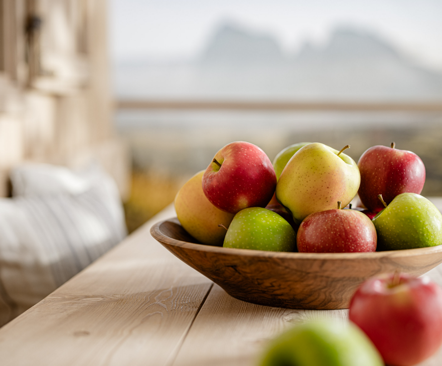 Cuenco de fruta con manzanas frescas variadas frente a un paisaje montañoso