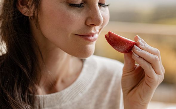 Mujer acercando la nariz a una manzana