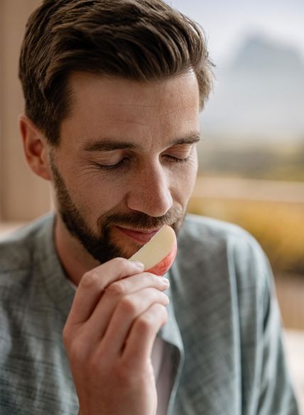 Uomo annusa un pezzo di mela tenuto in mano