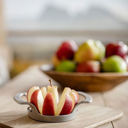 Manzana fresca cortada frente a cuenco con manzanas variadas, montañas visibles al fondo