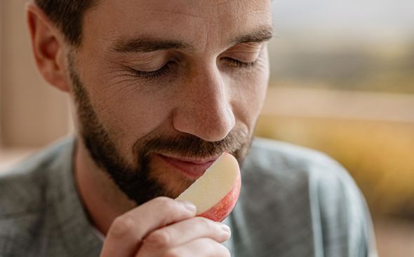 Hombre huele una manzana