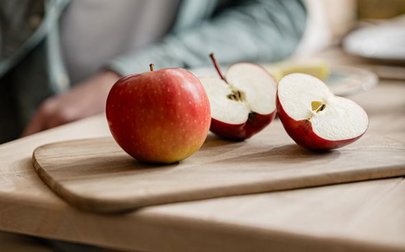 Hombre oliendo una manzana, en primer plano manzanas frescas, una cortada y otra entera