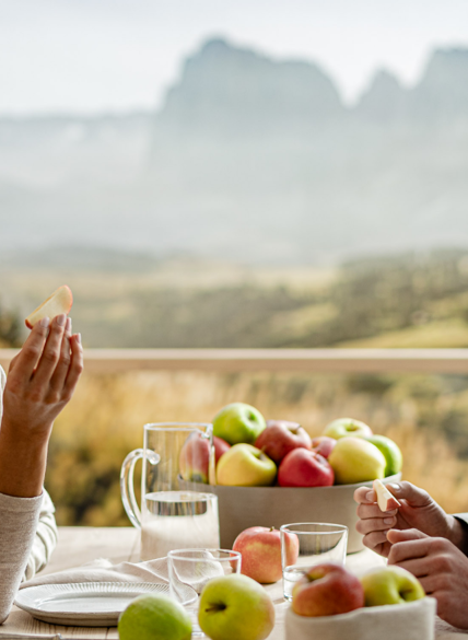 Pareja en mesa de madera con manzanas frescas, al fondo paisaje montañoso